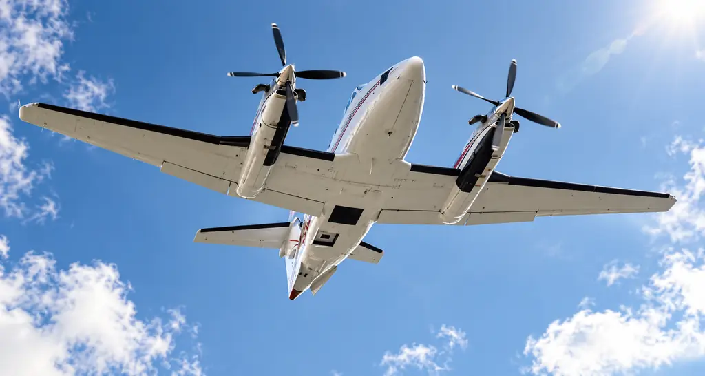 Twin turboprop special mission aircraft seen from below against a blue sky